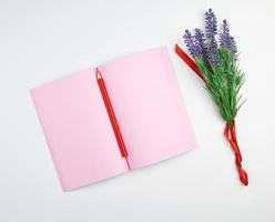 open notebook with blank pink pages, wooden red pencil photo