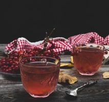 té caliente fresco de bayas de viburnum en una taza de vidrio transparente foto