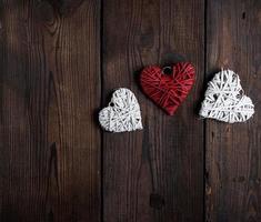 three wicker small hearts on a brown wooden background photo