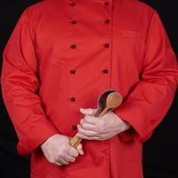 chef en uniforme rojo con cucharas de madera viejas foto