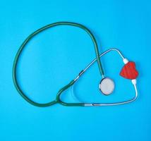 green medical stethoscope and red wooden heart photo