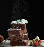 stack of square baked brownie chocolate cake slices sprinkled with white sugar photo