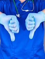 doctor in blue uniform and latex sterile gloves shows a gesture dislike photo