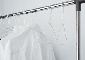 white men's crumpled shirts hanging on a metal hanger photo