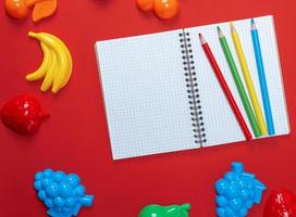 open notebook with empty white sheets and multicolored wooden pencils photo