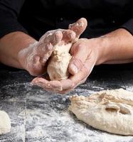 cocinero haciendo bolas de masa en una mesa de madera negra foto