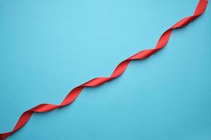 curled red satin ribbon on blue background photo