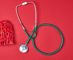 green medical stethoscope  on red background photo