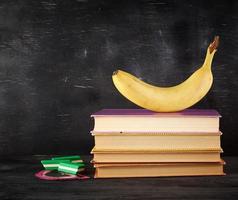 closed books with yellow sheets and ripe banana photo