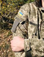 fragment of the hand of a Ukrainian soldier in military camouflage uniform with a patch of the Ukrainian flag photo