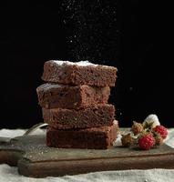 stack of square baked brownie chocolate cake slices sprinkled with white sugar photo