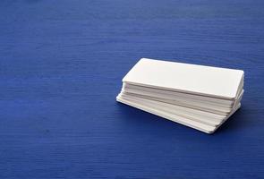 tarjetas de visita rectangulares de papel en blanco blanco sobre fondo de madera azul foto