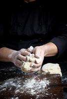 baker kneads white wheat flour dough photo