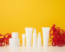 jar, bottle and empty white plastic tubes for cosmetics on a yellow background. Packaging for cream, gel, serum, advertising and product promotion, mock up photo