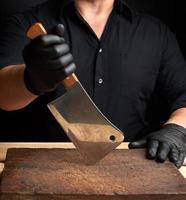 chef in a black shirt and black latex gloves holds a large kitchen knife photo