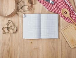 cuaderno abierto en blanco en línea y accesorios de cocina de madera foto