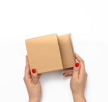 two female hands hold a square box made of brown corrugated cardboard on a white background photo