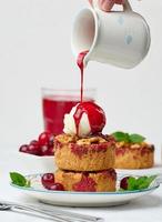 Cherry crumble pie decorated with a scoop of ice cream and poured with cherry sauce on a plate photo