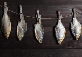 salted fish crucian hanging on a rope hooked on a wooden clothespin photo