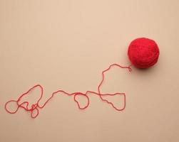 clew with red-woolen thread on a beige background photo