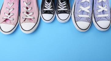 three pairs of textile worn shoes on a blue background photo