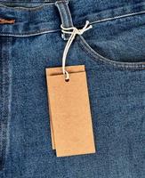 tied on a rope is an empty rectangular brown paper tag on blue jeans photo