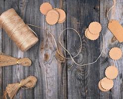 coil of brown rope, paper tags on a gray wooden background photo