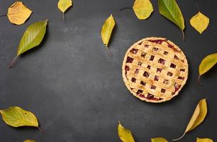 baked round pie with plums on a black background, top view. Place for inscription photo