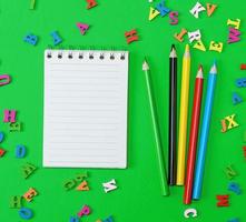 open notebook with blank white sheets in line, colored wooden pencils photo