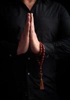 hombre adulto con una camisa negra dobló los brazos frente a su pecho en una pose de oración foto