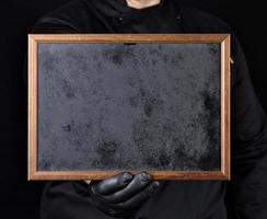 chef in black uniform holds an empty wooden frame photo