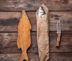 Fresh whole sea bass fish wrapped in a brown paper  and tied with a rope photo