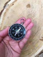 Compass on the right of the human hand on the background of hemp, a top view photo