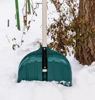 plastic green  shovel sticking out of a pile of snow photo