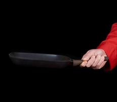 cocinar con uniforme rojo sosteniendo una sartén negra cuadrada vacía foto