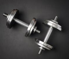 pair of shiny steel typesetting dumbbells for bodybuilding on a black background photo