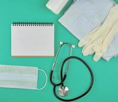 open notebook in line with white sheets, medical mask, stethoscope and bandage photo