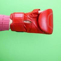 hand is wearing a red leather boxing glove on a green background photo