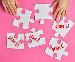 female hands holding empty paper puzzles, near objects with an inscription plan photo