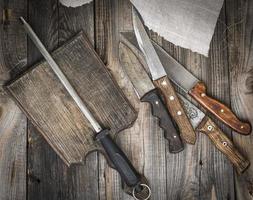 old brown wooden cutting board and knife with sharpening on the table photo