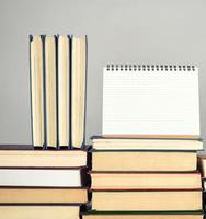open blank notebook is standing on the stack of books photo
