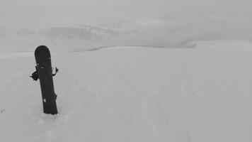 base preta de snowboard em uma neve com montanhas brancas ao fundo. conceito de nova temporada de esqui. video