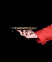 mano derecha del chef con uniforme rojo sosteniendo un plato de cobre vacío foto