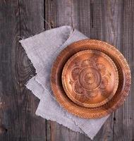 empty round brown carved decorative plate standing on a gray linen napkin photo