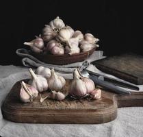 raw unpeeled garlic on a very old vintage cutting board and iron pres photo