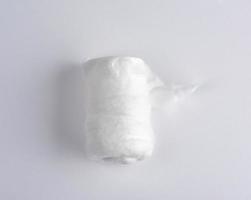 algodón médico blanco retorcido en un rollo sobre un fondo blanco foto