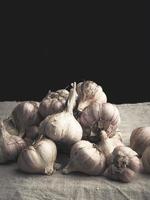 heap of raw unpeeled garlic on a vintage gray linen napkin photo
