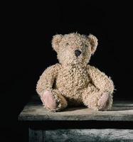 brown soft teddy bear sit on a  wooden background photo