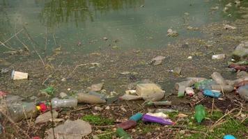 Contaminación de botellas y bolsas de plástico en el estanque. video