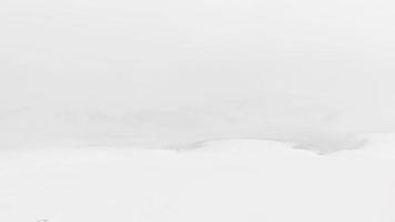 Snowboarder allein im schwarzen Outfit stehen bei stürmischem Wetter vor dem Freeriden bergab auf Aussichtspunkt. Lawinengefahr und extreme Winterwetter-Schneeverhältnisse